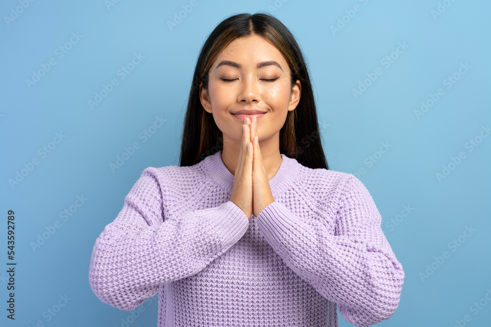 Gorgeous woman has calm facial expression, keeping palms pressed together Gorgeous woman has calm facial expression, keeping palms pressed together
