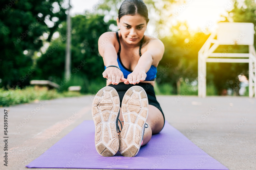 Sporty girl stretching her legs sitting on a mat in a park. Athlete ...