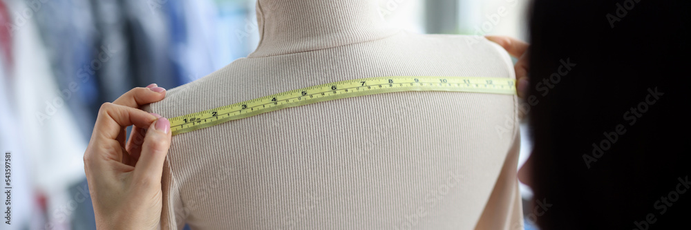 Female fashion designer takes measurements with centimeter
