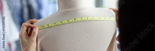 Female fashion designer takes measurements with centimeter
