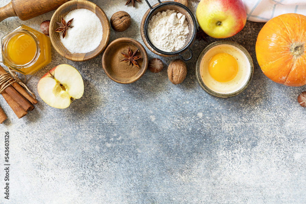 Baking food background. Pumpkins, apples, honey, nuts and seasonal spices for pumpkin or apple pie on a gray tabletop. View from above. Copy space. Baking food background. Pumpkins, apples, honey, nuts and seasonal spices for pumpkin or apple pie on a gray tabletop. View from above. Copy space.