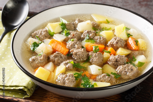 Satisfying sodd is Norway national dish which usually consists of mutton, meatballs, carrots, and potatoes served in a clear, fragrant broth closeup in the plate on the table. Horizontal