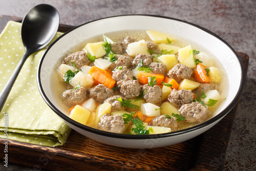 Sodd is a traditional Norwegian soup like meal with mutton, meatballs, potatoes and carrots closeup in the plate on the table. Horizontal