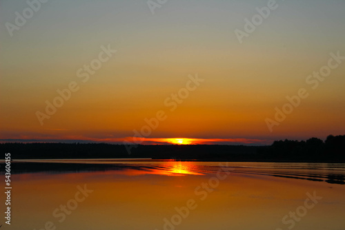 Sunset in strong colors over a river with reflections of trees