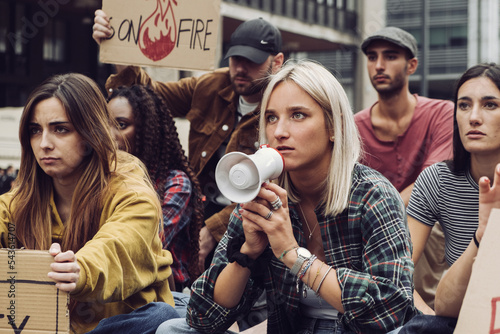 young protester sit-in - group of generation z people protesting against global warming