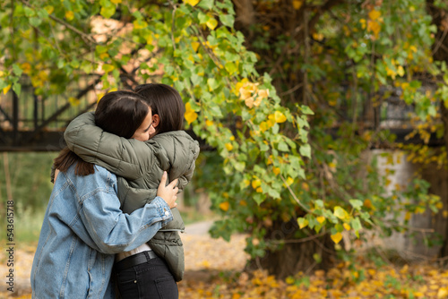 Young lesbian couple embracing in a park on an autumn day.