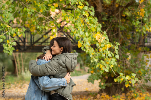 Young female couple embracing in a park on an autumn day.
