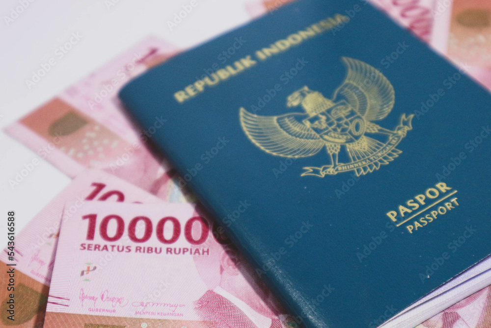 Indonesian green passport with a collection of hundred thousand rupiah as the background. Indonesian green passport with a collection of hundred thousand rupiah as the background.