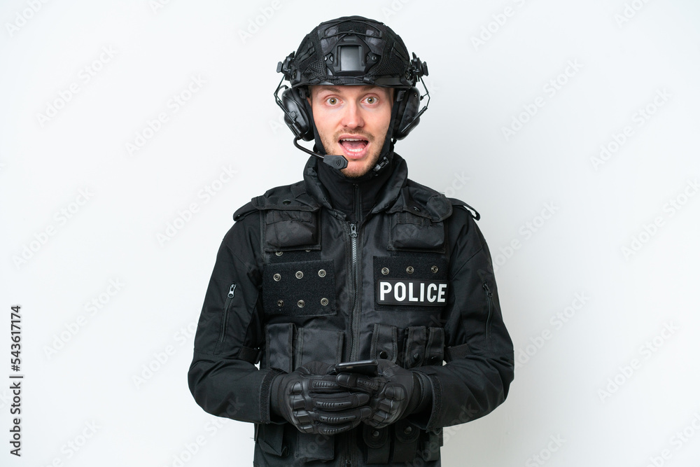 SWAT man over isolated white background surprised and sending a message SWAT man over isolated white background surprised and sending a message