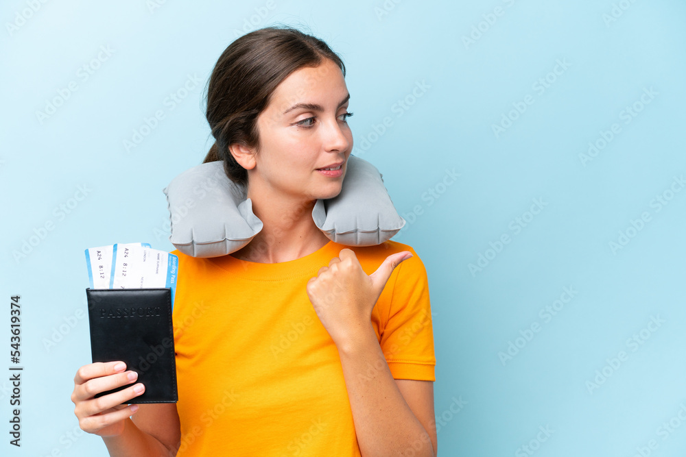 Naklejka premium Young beautiful woman with Inflatable travel Pillow isolated on blue background pointing to the side to present a product