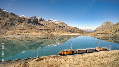 Small freight train on rails near a high mountain lake photo