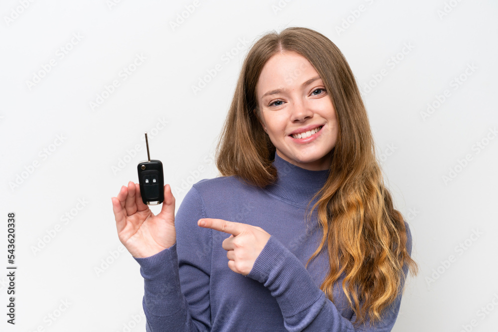 Young caucasian woman holding car keys isolated on white background and pointing it Young caucasian woman holding car keys isolated on white background and pointing it