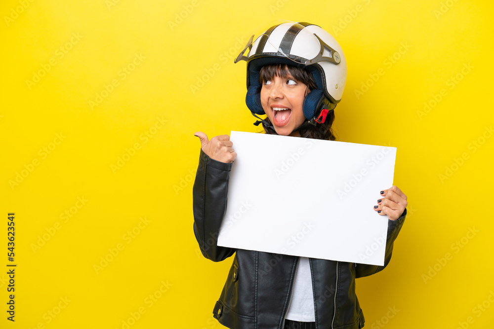 Young latin woman with a motorcycle helmet isolated on yellow background holding an empty placard and pointing side Young latin woman with a motorcycle helmet isolated on yellow background holding an empty placard and pointing side