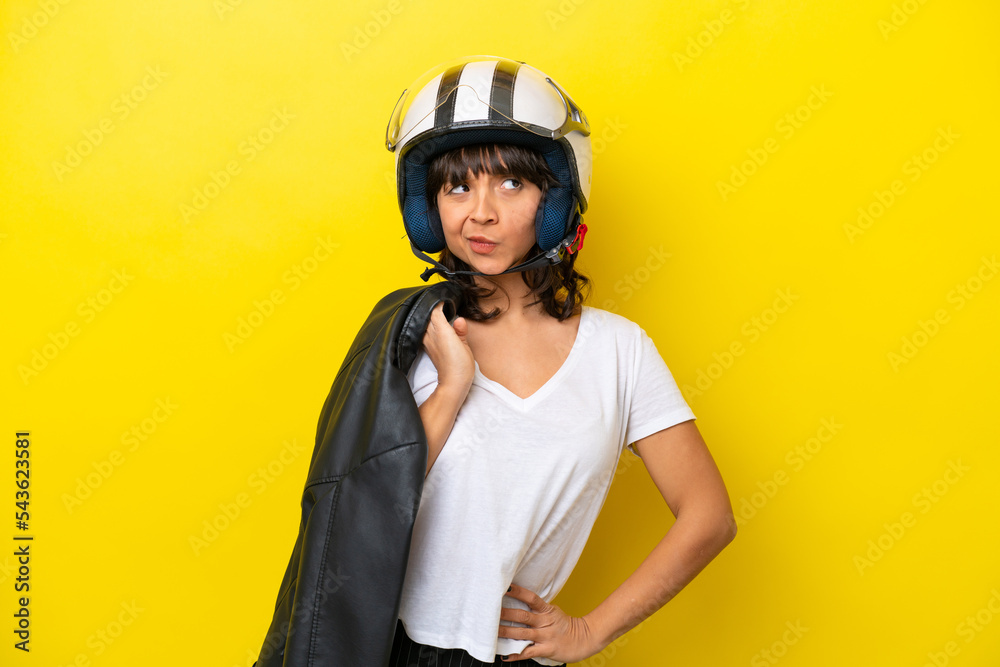 Young latin woman with a motorcycle helmet isolated on yellow background Young latin woman with a motorcycle helmet isolated on yellow background