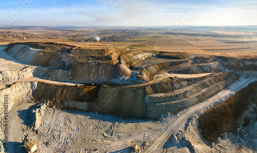 Aerial view of open pit mining site of limestone materials for construction industry with excavators and dump trucks