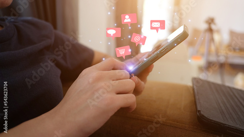 women using a social media marketing concept on mobile smart phone with notification icons of love, message, comment, chat, email. and shopping cart smartphone hologram screen