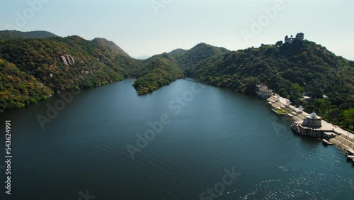 Pan aerial drone shot showing the dam and shiva temple on the edge of dhebar lake with hawa mahal veerpura in distance and the various cenotaph on the edge a popular tourist spot panning to lake photo