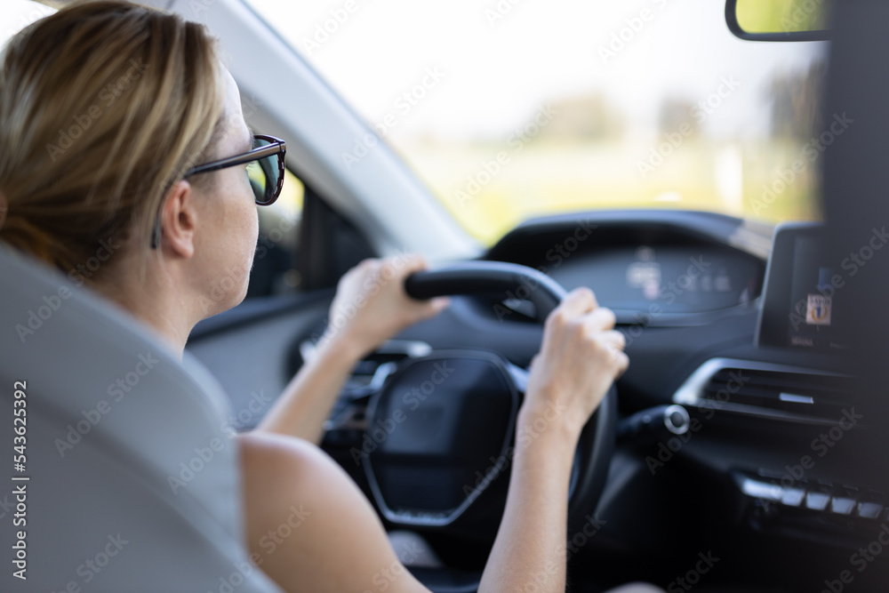 Business woman driving a car to work. Female driver steering car on the road