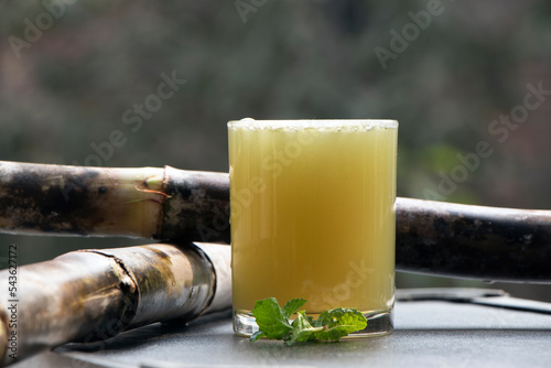 focus on fresh Sugarcane juice glass with raw sugarcane around it 