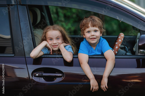 Children in the car window have fun, laugh, rejoice.