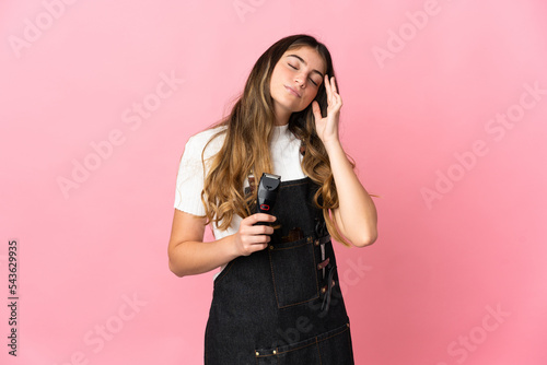 Young hairdresser woman isolated on pink background with headache