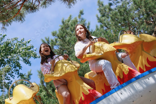 Teenage girls ride on carousels in the park. © olgasparrow