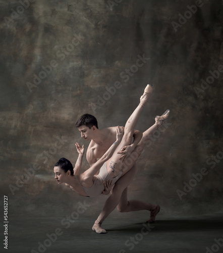 Young man and woman, professional ballet dancers performing isolated over dark green vintage background © Lustre