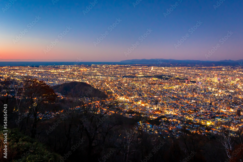 藻岩山の展望台から見た札幌市の夜景と、夕焼けから夜に変わる空