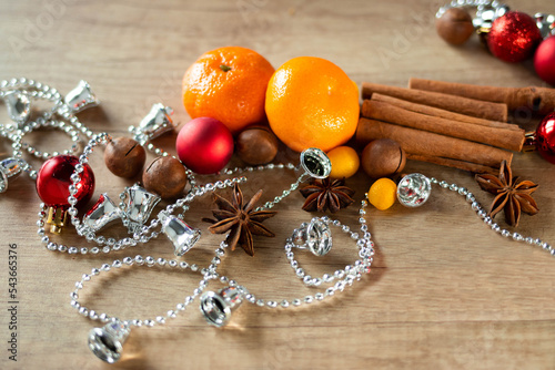 Christmas decorations, tangerines, and spices lie on a wooden background. The concept of the New Year and Christmas time