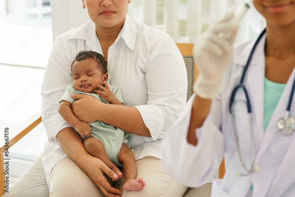 Obraz premium Mother holding newborn baby boy one-month-old mixed-race African-Thai, visiting the doctor for checkup health with stethoscope at the clinic pediatric. concept consultation, nurse, healing infant.