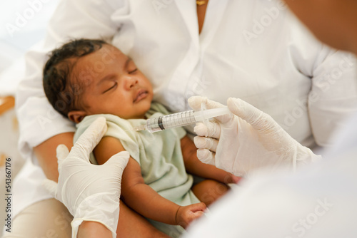 Close up of the hand and needle. Doctor holds syringe to vaccinate newborn baby one month old with injection. Concept clinic pediatrician health check Vaccine antivirus for infant.
