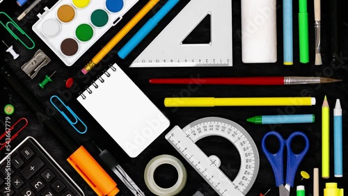 Horizontal composition of colorful school supplies moving downwards on blackboard background. School and Education concept. Seamless looping. High quality 4k video.