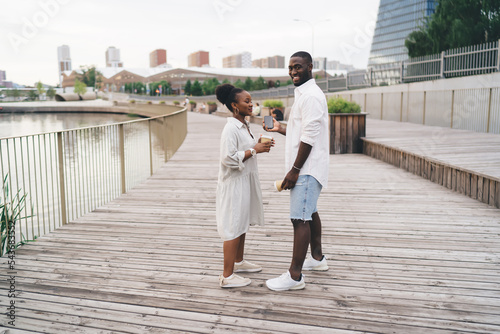 Stampa su tela Cheerful black couple standing on wooden embankment