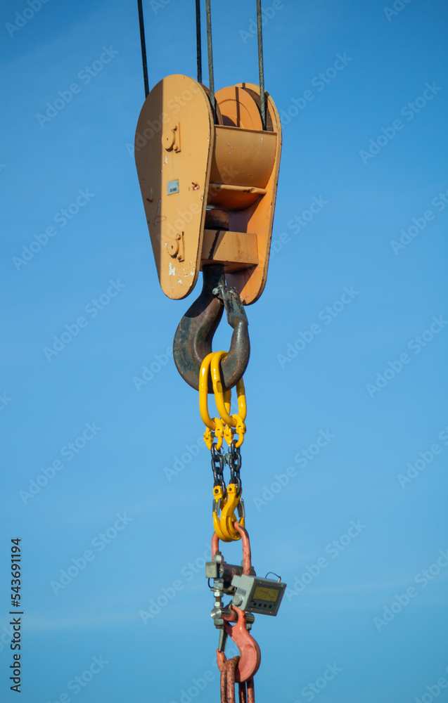 Heavy-duty lifting equipment featuring a robust crane hook and sturdy chains against a clear blue sky backdrop. Heavy-duty lifting equipment featuring a robust crane hook and sturdy chains against a clear blue sky backdrop.