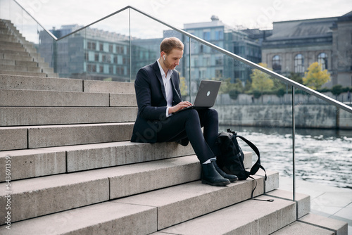 Canvas Print Businessman working on his laptop sitting outside