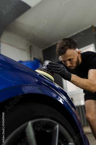 Hard wax car polishing with orbital polisher for remove scratches close-up. Working process in detailing auto service.
