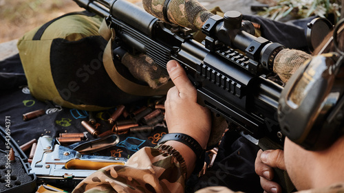 The shooter fires from cover in the means of hearing protection from a Kalashnikov assault rifle