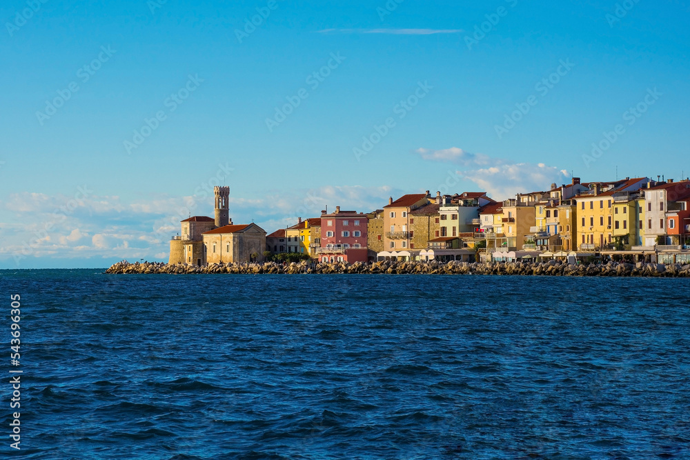 The waterfront of the historic medieval town of Piran on the coast of Slovenia. On the far left is the Our Lady of Health Church and a 17th century lighthouse tower 
