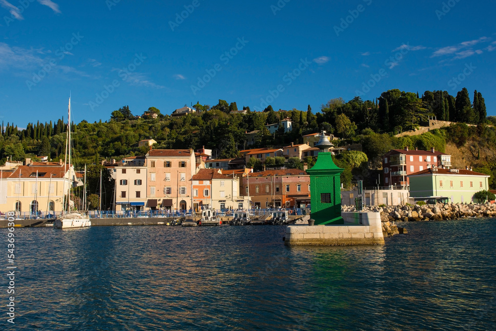 A small green lighthouse on the waterfront of the historic medieval town of Piran on the coast of Slovenia
