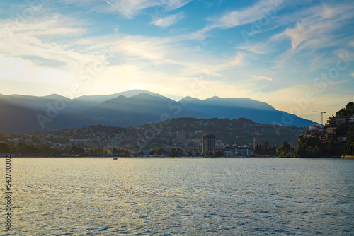 Stunning landscape of picturesque Lake Lugano and the green lush Swiss Alps in the distance during idyllicsunset in Lugano, Switzerland. photo