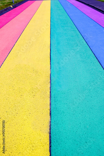 Vertical picture of street road painted in rainbow colors or lgtb flag.