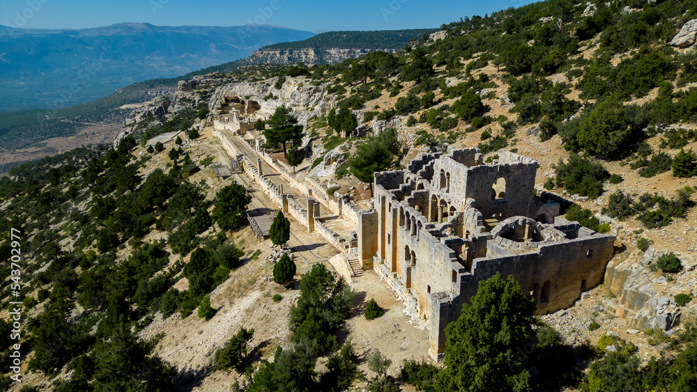 Fototapeta premium It has a unique topographic location on the slopes of the Taurus Mountains, two richly decorated large churches, a baptistery, a columned road, rock tombs, water springs, a bath and accommodation.