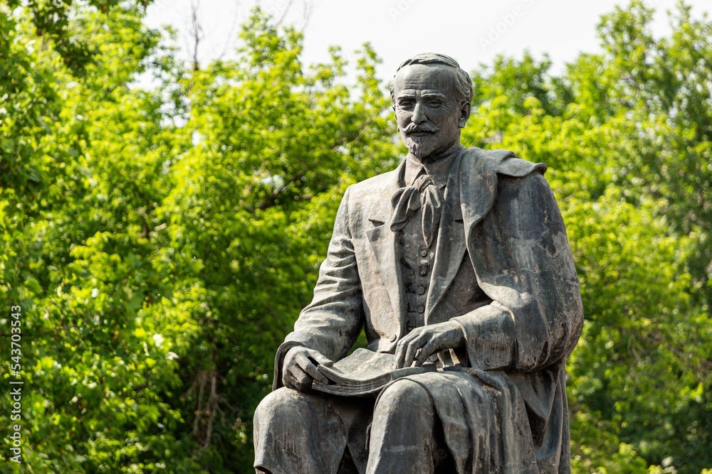 Fototapeta premium Horizontal image of statue of poet and writer Hovhannes Tumanyan in the background of trees