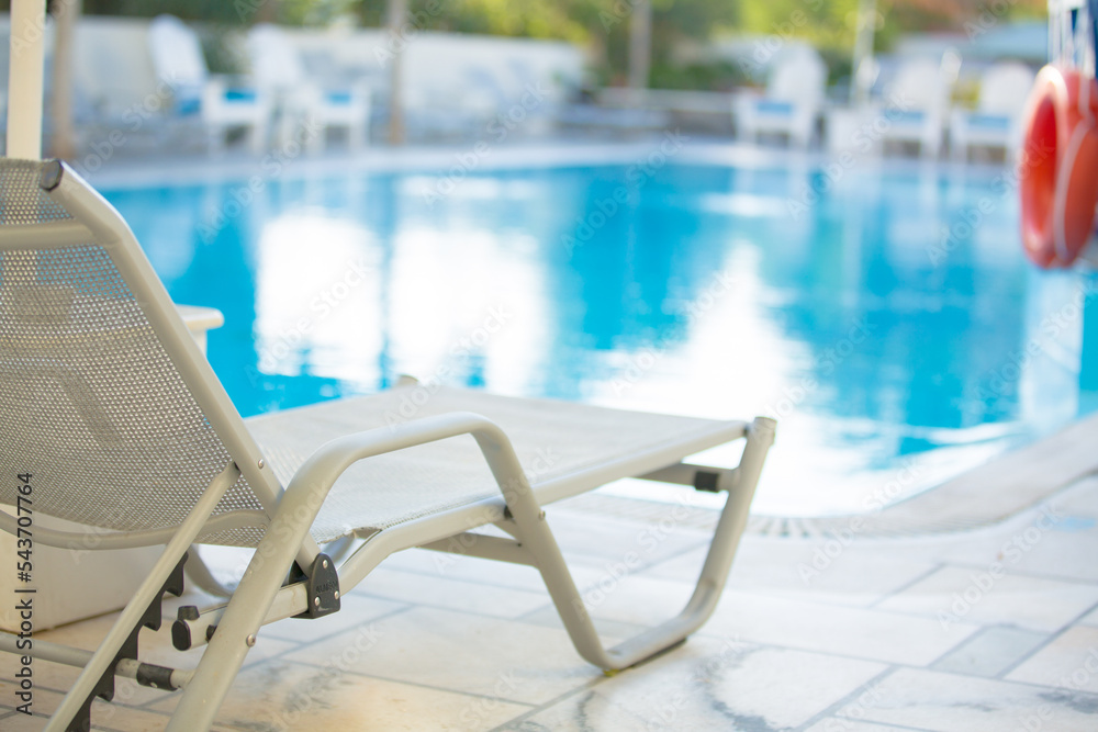 Sun loungers by the pool with water next to the hotel Sun loungers by the pool with water next to the hotel
