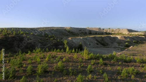 Flying over the hill revealing forests in the distance. Aerial landscape photo