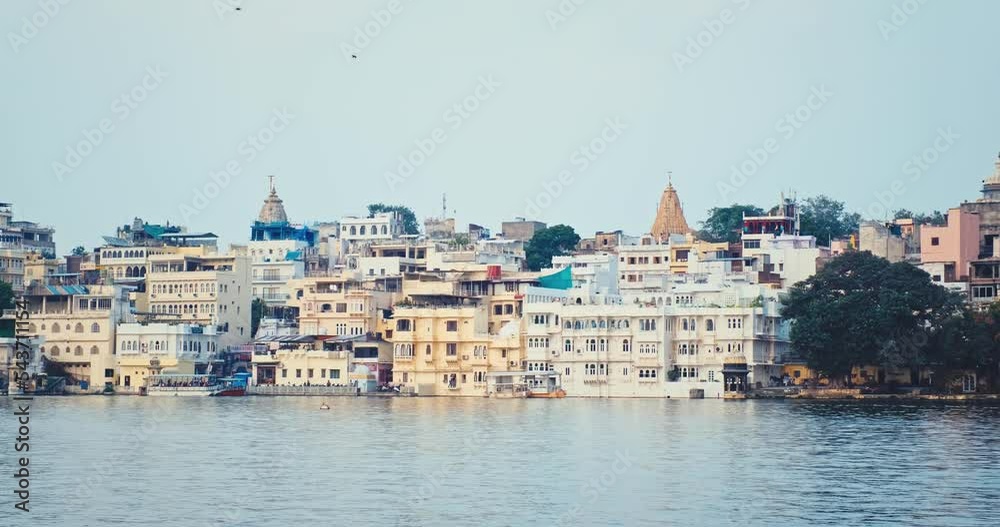 Udaipur Lal ghat and luxury Udaipur City Palace view over lake Pichola with tourist boat. Rajput architecture of Mewar dynasty rulers tourist Indian landmark. Incredible India. Horizontal camera pan Udaipur Lal ghat and luxury Udaipur City Palace view over lake Pichola with tourist boat. Rajput architecture of Mewar dynasty rulers tourist Indian landmark. Incredible India. Horizontal camera pan