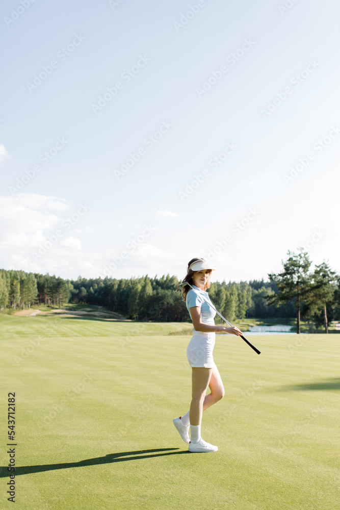 Woman in stylish summer golf outfit walking on beautiful green course for golf game. High quality photo
