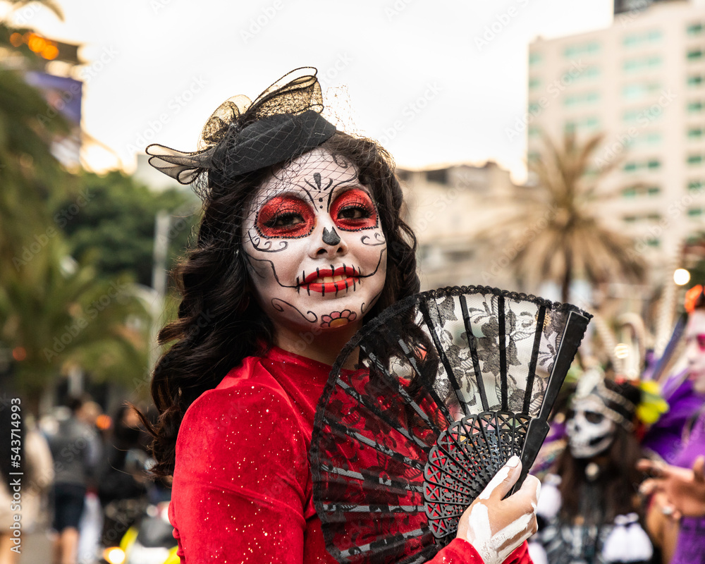 Mujer joven caracterizada como catrina con abanico negro y vestido rojo en  el desfile de las Catrinas, Ciudad de México. Stock Photo | Adobe Stock