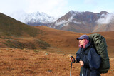 A young woman hiking in the mountains, wearing a raincoat and a tourist backpack. Passion for mountain tourism, backpacking
