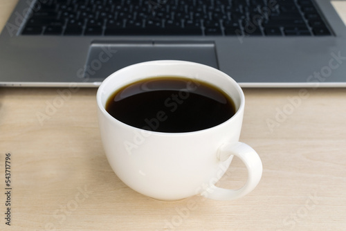 A cup of coffee on the background of a laptop computer. Morning. Work online. Break. Webinar